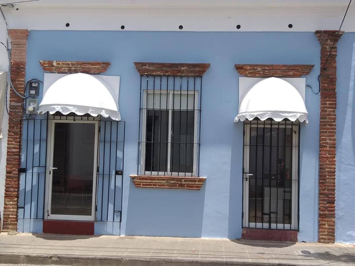 La Aldea 124: blue facade with barred windows and white awnings on Calle Sánchez