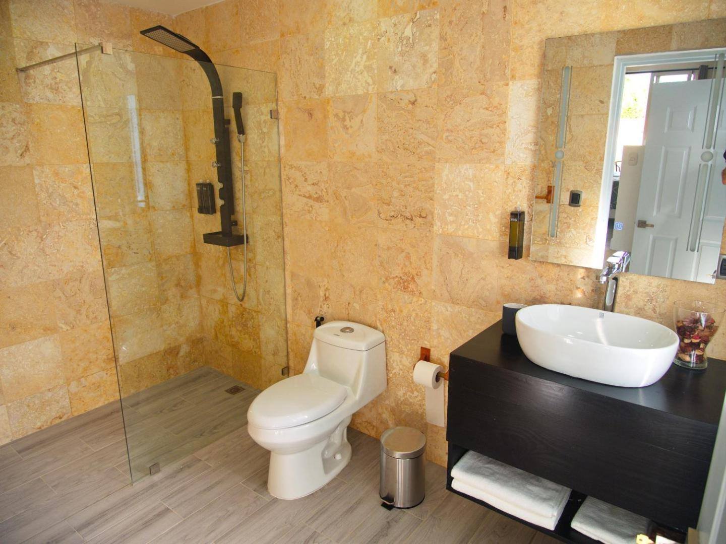 La Aldea 124: bathroom with light stone, a vessel sink and a glass shower